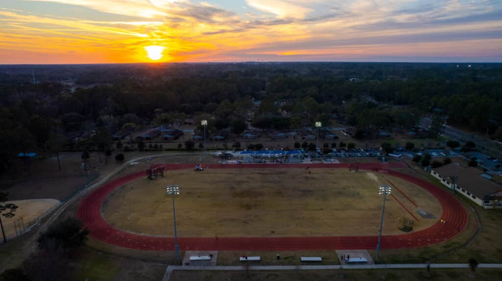 Aerial view of a Gainesville running club track and field at sunset.