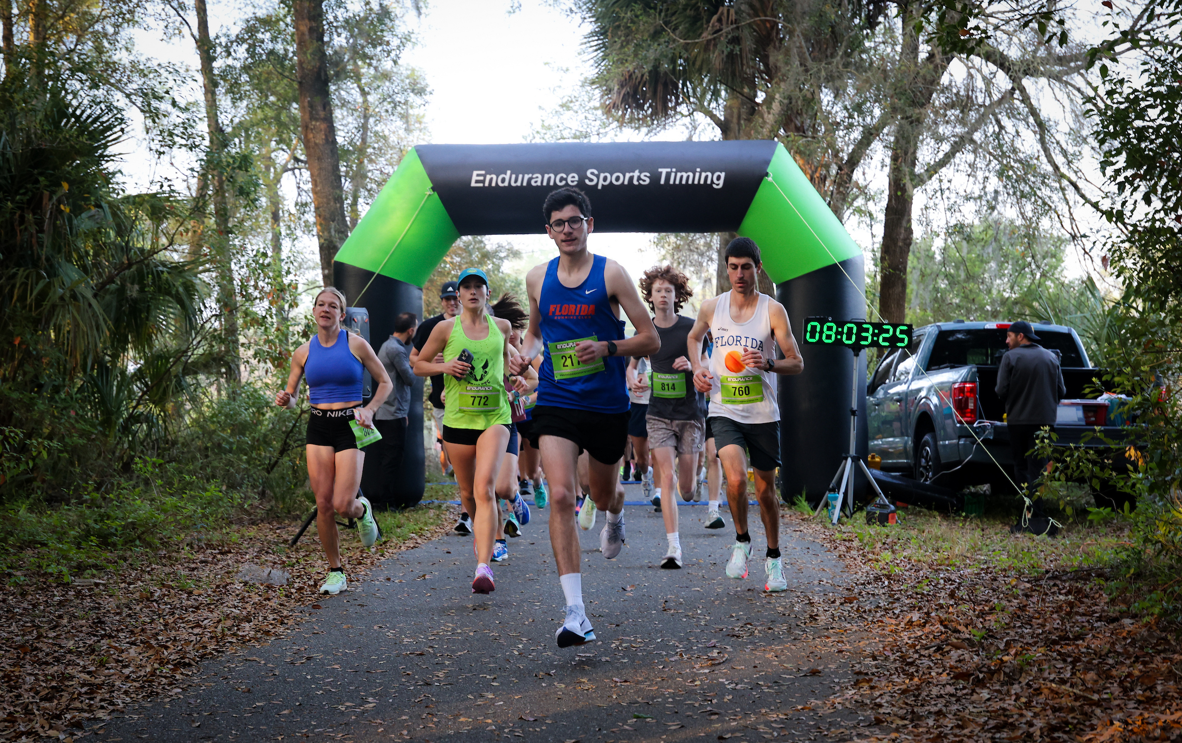 A group from the Gainesville Running Club in athletic wear passes through a finish line arch marked “Endurance Sports Timing” during a road race.