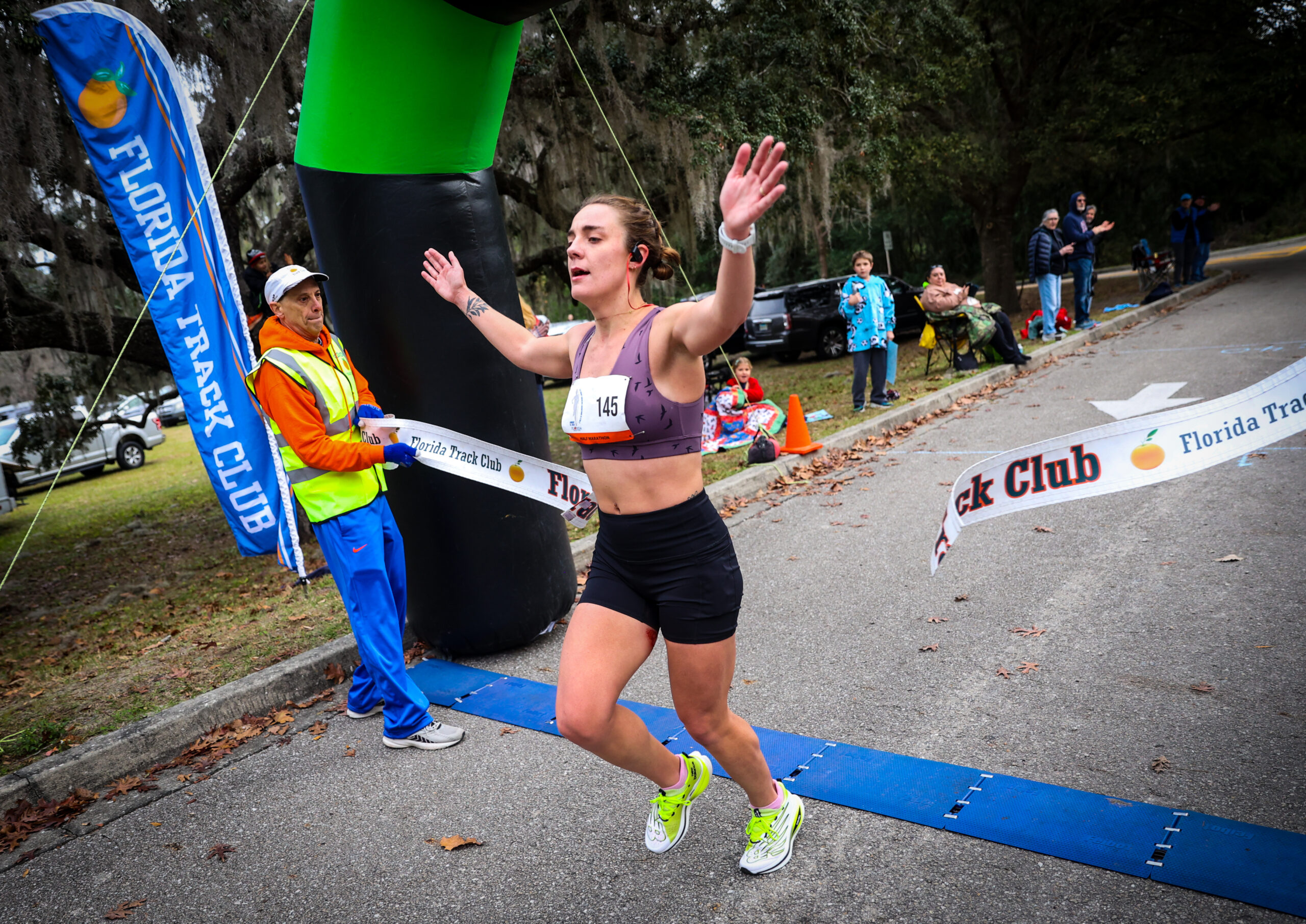 A runner with race bib 145 celebrates as she crosses the Florida Track Club finish line, marking a victory for the Gainesville run club.